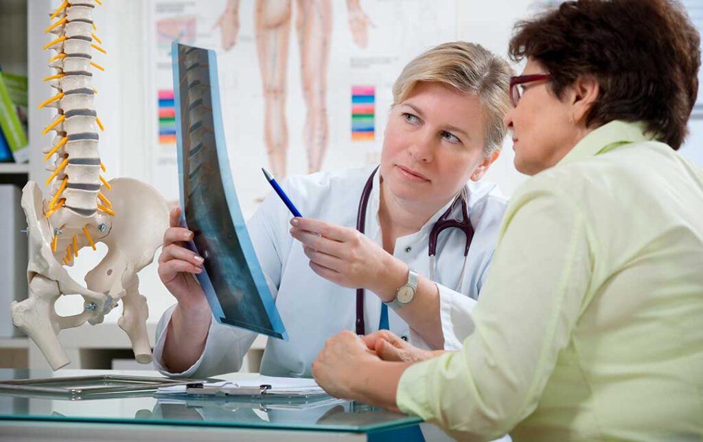 A chiropractor performs a gentle joint adjustment on a middle-aged athlete’s knee in a clinical setting.