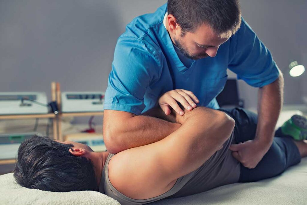 A clinician discusses back pain with an adult during a spine and movement assessment.